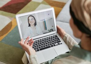 person on laptop talks with a doctor through telehealth treatment services